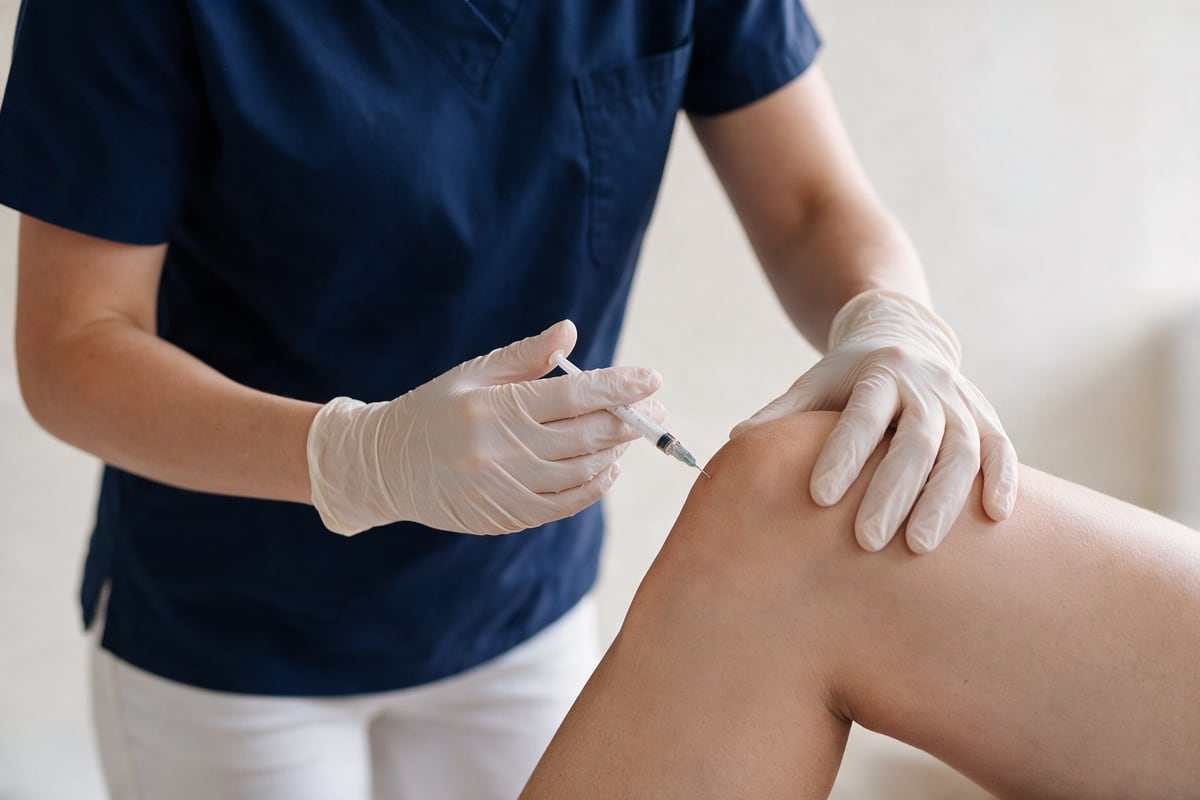 Ärztin führt eine Infiltration am Knie durch.