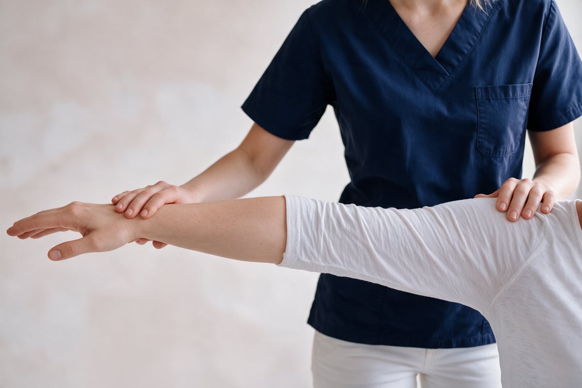 Physiotherapeutin begleitet eine Patientin bei einer Schulterübung.